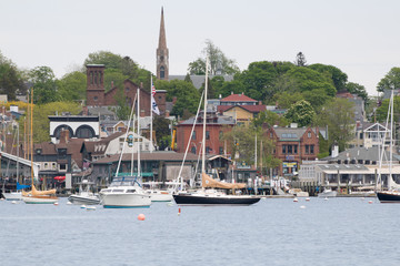 Newport Harbor in Newport, Rhode Island. The brown steeple is the historic St. Mary's Church where John F. Kennedy was married. Sailboats and moorings are in the foreground. Seaside, coastal town - obrazy, fototapety, plakaty