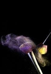 Make-up brushes with powder dust on black background