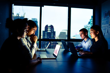 businessman and businesswoman working with computer overtime at night and low light