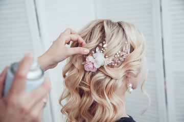 Naklejka premium Hair stylist fixes the styling with a hair spray. Hairdresser at work.