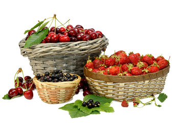 Summer gifts: cherry, strawberry and black currant in wicker baskets isolated on white.