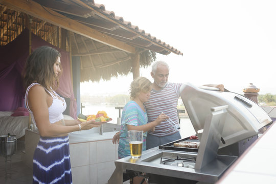 Family Barbecue With Older Man, Young Woman And Girl On A Penthouse Terrace