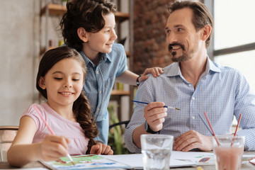 Father and son communicating while daughter painting