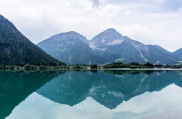 Heiterwanger See mit Spiegelung der Bergkette im Wasser - Tirol, Österreich.