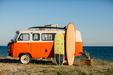 bus with a surfboard on the roof is a parked near the beach