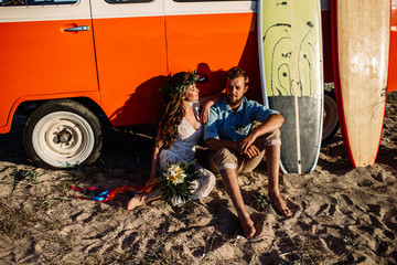 Happy surfers couple standing with surfboards on the sandy beach