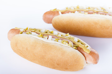 Hot dog grill with mustard, onion and pickles isolated on white background.