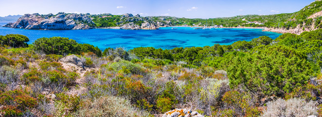 Sea bay with azure blue water surrounded by rocks on coast of Maddalena island, Sardinia, Italy