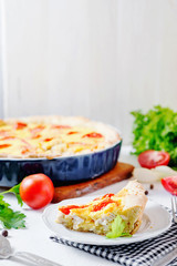 French open pie from short pastry, kish, tart with chicken, cherry tomatoes, greens and creamy cheese cress, filling, sauce and spices, pepper, lettuce and salt on white rustic background