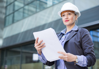Employee woman in helmet with paper documents