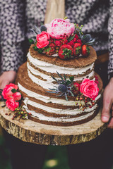 groom hold wedding cake with flowers
