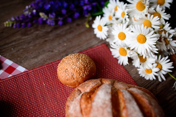 Obraz na płótnie Canvas Close up on traditional bread on the table, next to flowers daisies and lupins