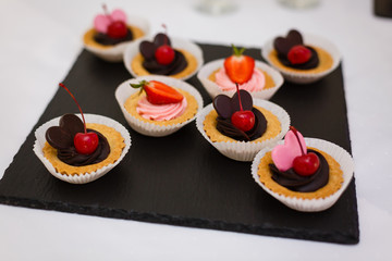 Delicious chocolate cupcakes with berries on white table, top view
