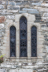 Fototapeta na wymiar Old stained glass window on stone wall of medieval stone church in Norway