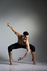 Young and stylish modern ballet dancer on grey background