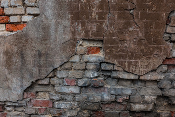 The old brick and stone wall with plaster