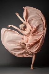 Gordijnen Woman in light chiffon dress dancing sensually on black plain background. © julenochek