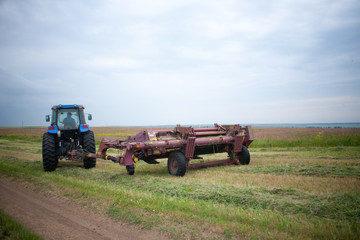 Fototapeta premium pasture mowing with blue tractor and mower