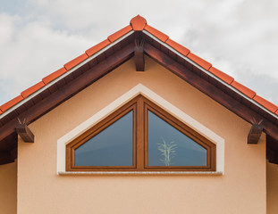 Moderner Giebel eines Neubaus mit Trapezfenster in PVC als Holzimitat - Modern pediment of a new...