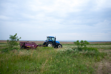 pasture mowing with blue tractor and mower