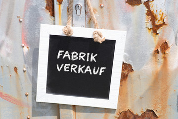 Eine alte Tür und eine Kreidetafel mit dem Wort Fabrikverkauf