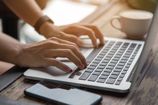 woman hands on laptop with mobile phone and coffee