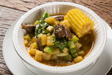 South American cuisine: Puchero soup with chickpeas close-up in a pot on the table.