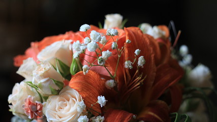 Cream roses,orange lilies and tiny white flowers,details of the wedding bouquet