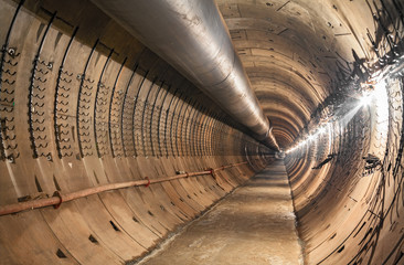 Empty underground tunnel under construction for the metro. Large temporary ventilation pipe under...