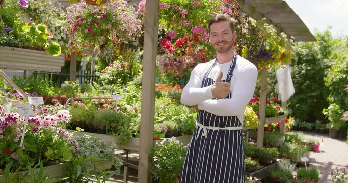Smiling handsome gardener man standing with arms crossed and looking at camera in the sunny day.