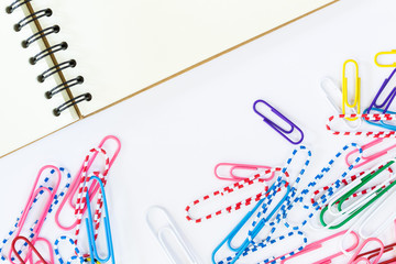 note book and paper clips on white background