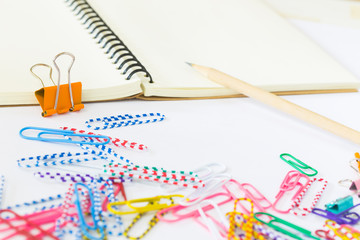 note book and paper clips on white background