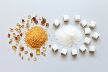 White refined and brown cane sugar on a light gray background