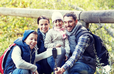 Obraz premium happy family with smartphone selfie stick in woods
