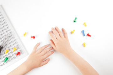 Top view on child's hands playing with colorful toys tools on the white background.
