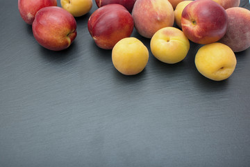 Ripe apricot and nectarine on black background of slate or stone