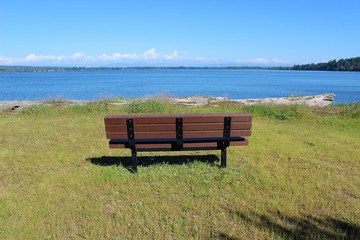 An empty bench with a beautiful bay view waiting for someone to sit and relax 
