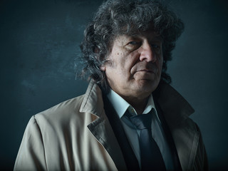 The senior man as detective or boss of mafia on gray studio background