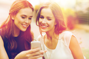 happy young women with smartphone at outdoor cafe
