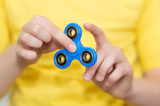 A boy is playing a popular toy fidget spinner in his hands. Stress relief. Anti stress and relaxation fidgets, spinner for tired people. Boy playing with a fidget spinner.