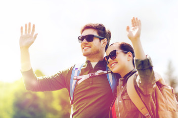 happy couple with backpacks hiking outdoors