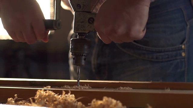 The carpenter uses a hand-held vintage drill in his work place. Slow motion