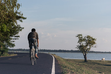 Man riding bike in the countryside on the road near the river