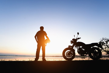 Silhouette of a biker  on the hill with sunset background, enjoying freedom and active lifestyle,...