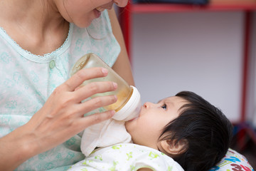 Obraz na płótnie Canvas Mother feeding newborn son with feeding bottle