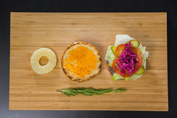 Open burger with pineapple on wooden board