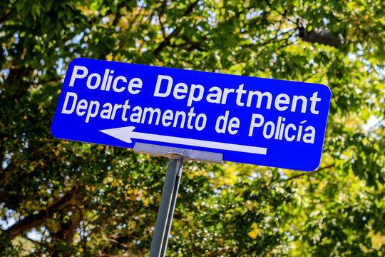 Blue aand white Police Department sign in both Englis and Spanish