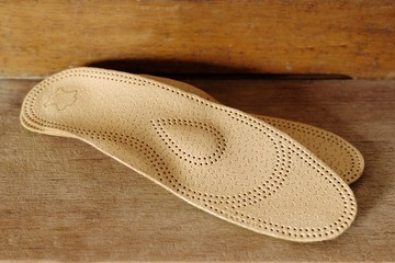 Orthopedic arch support made from leather on a wooden ground
