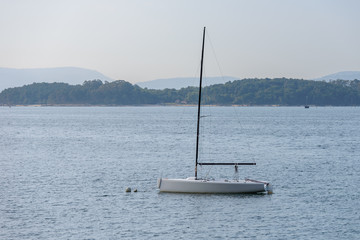 sailing boat with deflated sails moored near the shore
