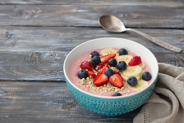 Healthy raw breakfast: porridge of sprouted green buckwheat with strawberries, blueberries and bananas on a wooden table